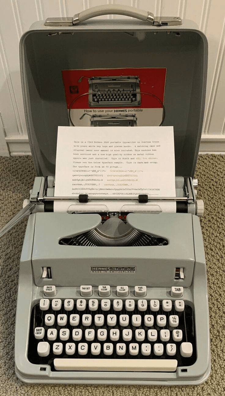 A grey mid-century portable typewriter with a typed page in the platen